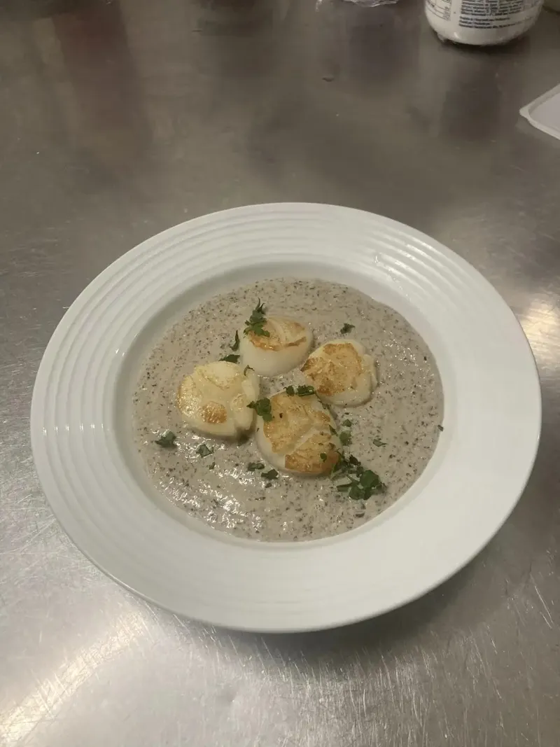 Noix de Saint-Jacques dorées sur un velouté de champignons, préparées dans la cuisine de Chez Lili
